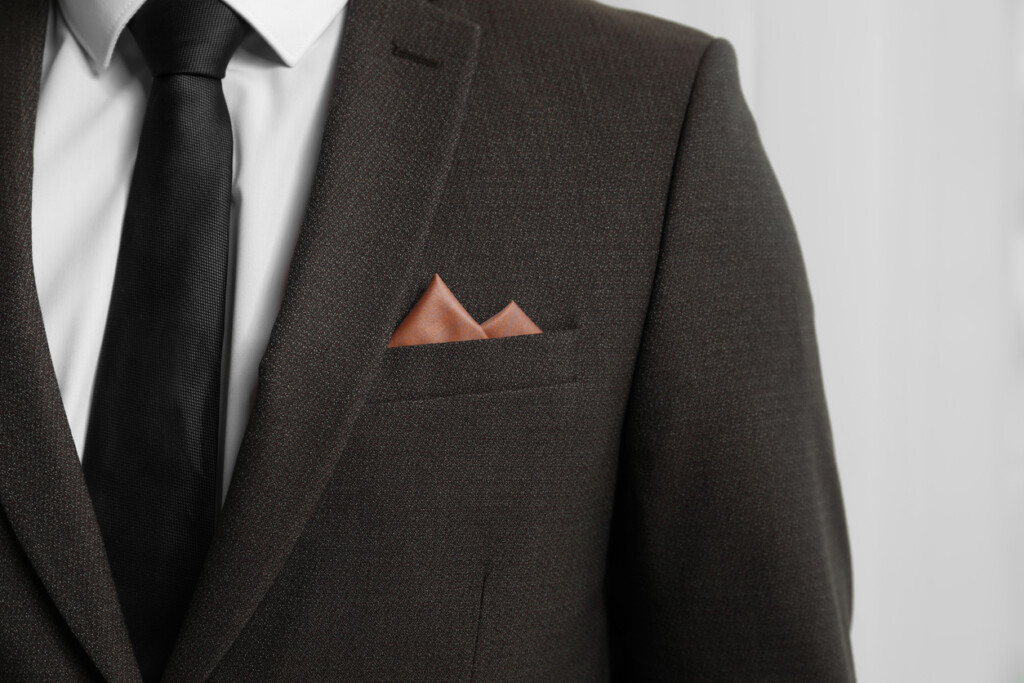 Man with handkerchief in breast pocket of his suit on light background, closeup